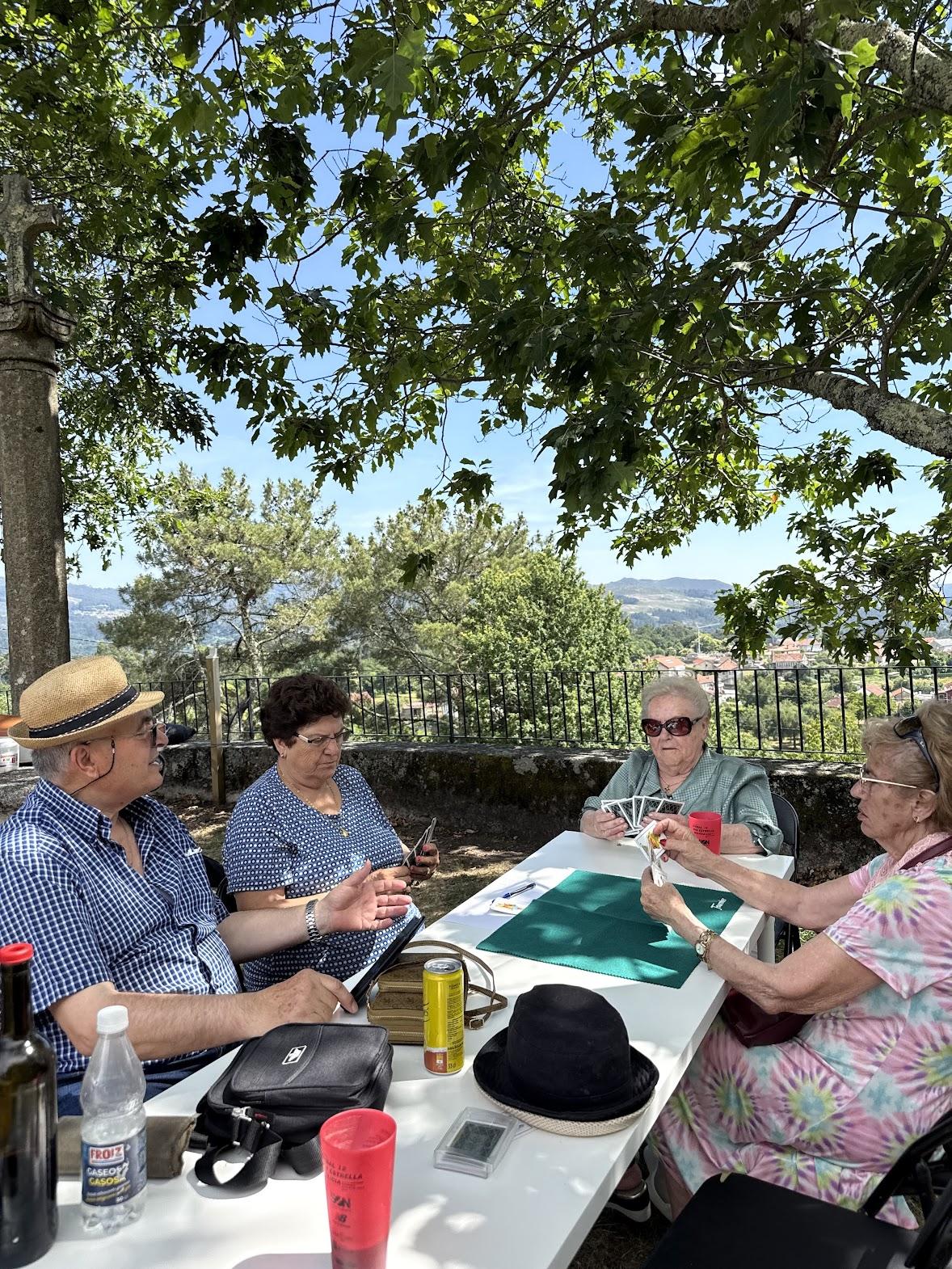 Veciños xogando ás cartas ao aire libre na casa do pobo